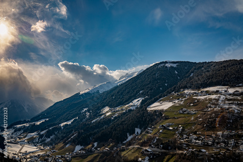 Clouds, snow mountains and Tyrolean village in the foreground.2021