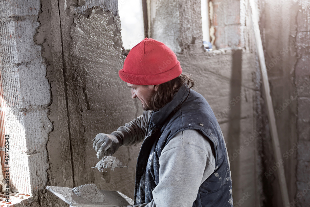 Real construction worker working on a wall inside the new house. Real construction worker working on a wall inside the new house.