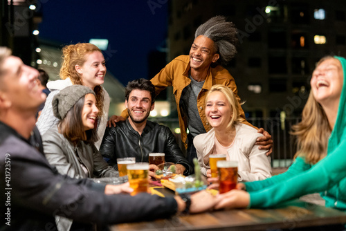 celebration party of millennial people  multi ethnic group of friends having fun and drinking beers  nightlife hangout of students and young couples