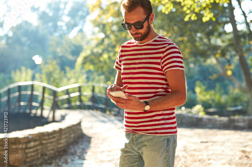Young adult man using modern smartphone in the park.