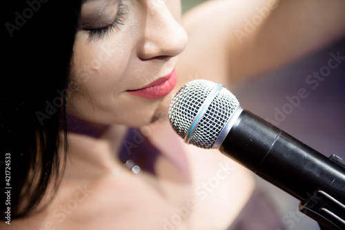 Female singer, performing her vocal sound on the scene with spotlight.