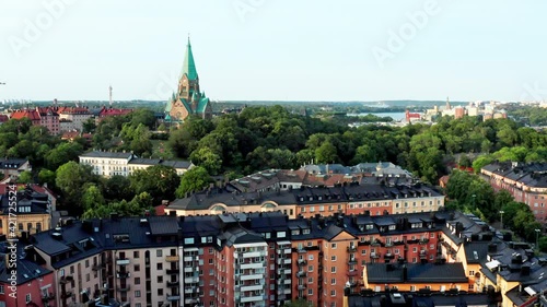 Stockholm, Sweden. Panoramic aerial flying drone view of Södermalm, Sofia church tower, Sofiakyrkan, Vitabergsparken, trendy SoFo rooftops, park and city. photo