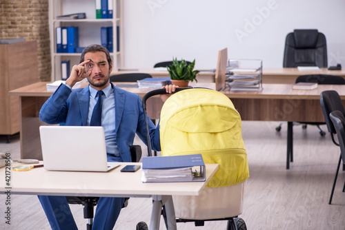 Young male employee looking after new born at workplace