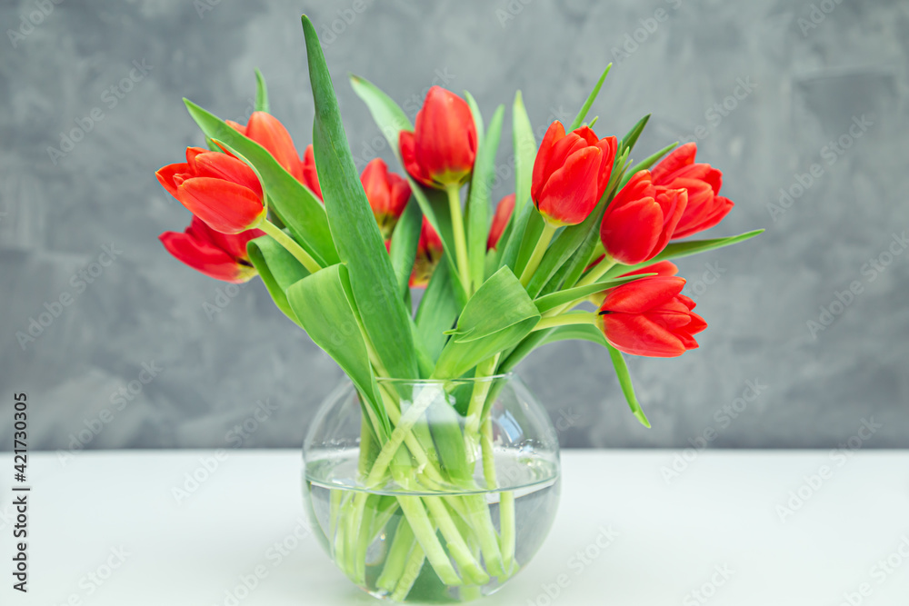Bouquet of red tulips in a vase on a gray background. Bouquet of red tulips in a vase on a gray background.