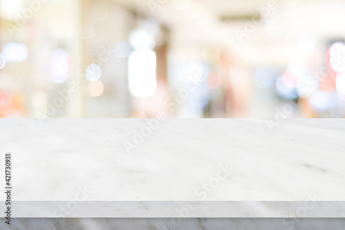 Empty white table top, counter, desk over blur perspective store with bokeh light background, White marble stone table, shelf and blurred shop for food, product display mockup, template 