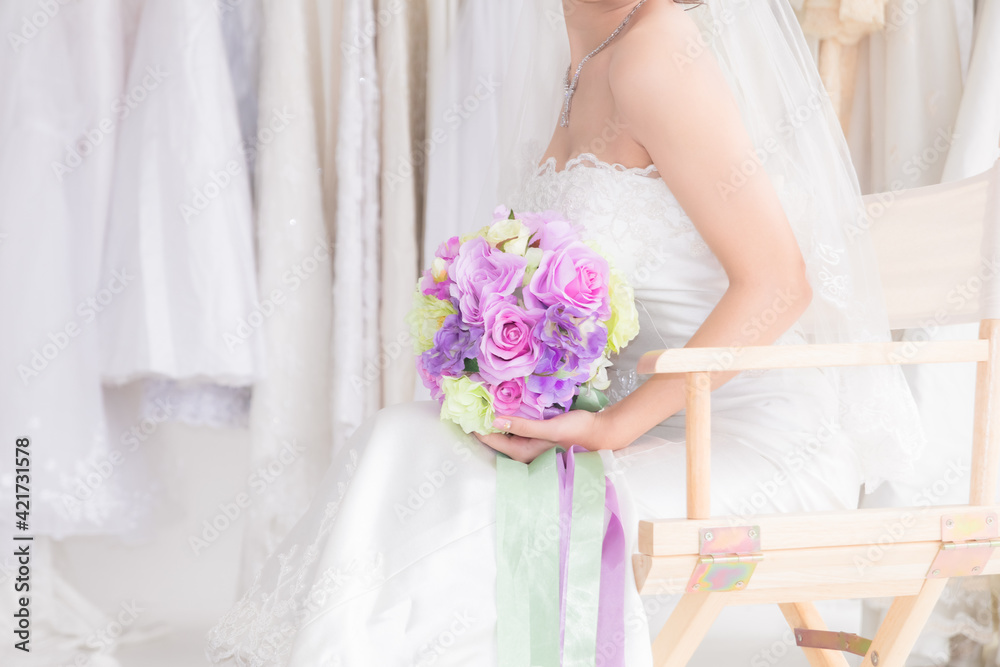 Beautiful Asian bride in wedding dress concept, happy girl hold flowers bouquet dream to her wedding date plan to shopping, woman in bridal dress with colorful floral bouquet in fitting room