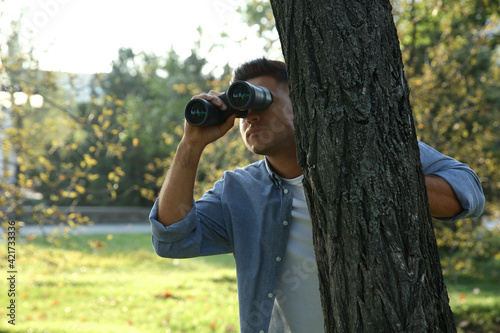 Jealous man with binoculars spying on ex girlfriend in park