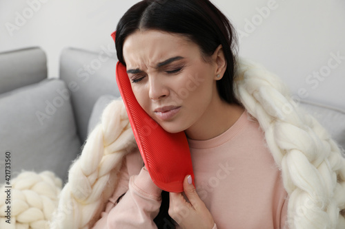 Canvas Print Woman using hot water bottle to relieve pain at home