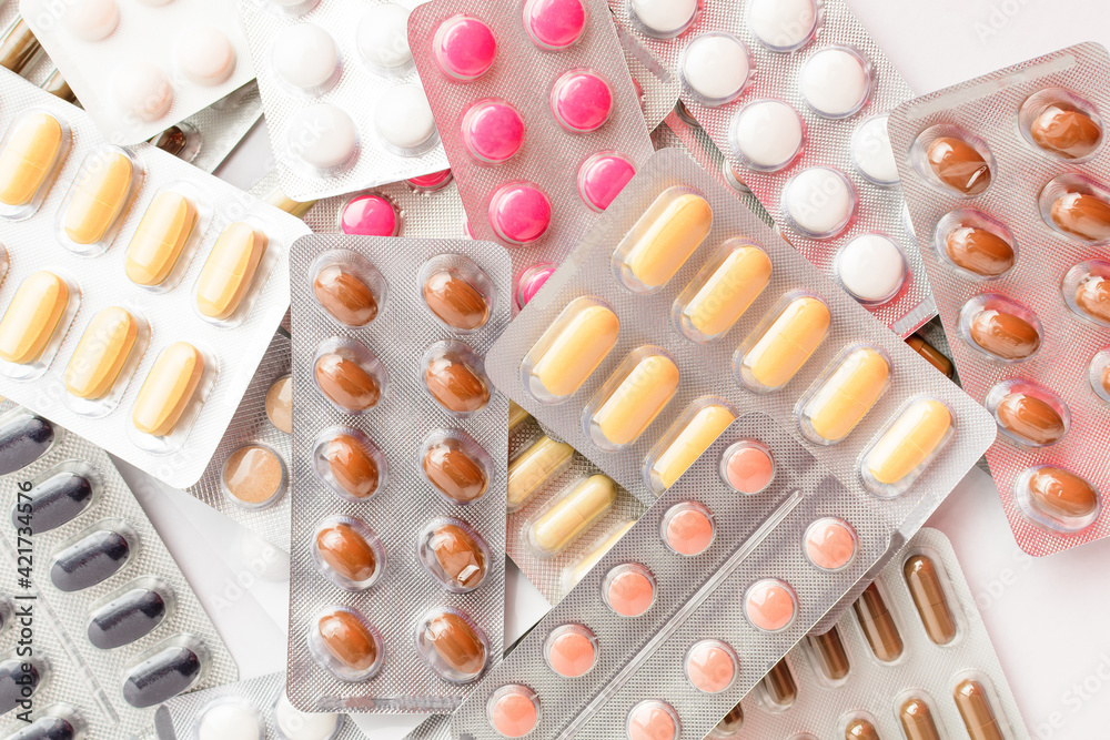 Close up of different medicine pills, tablets and vitamins isolated on white background, pharmaceutical picture taken with soft focus.