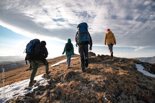 Group of diverse tourists or hikers walks on mountain top photo