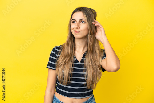 Young caucasian woman isolated on yellow background having doubts