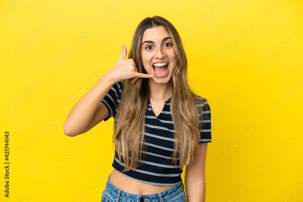 Young caucasian woman isolated on yellow background making phone gesture. Call me back sign Young caucasian woman isolated on yellow background making phone gesture. Call me back sign