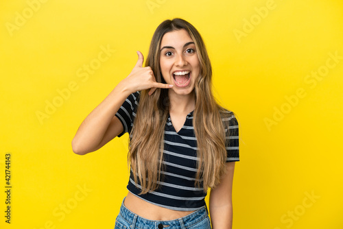 Young caucasian woman isolated on yellow background making phone gesture. Call me back sign
