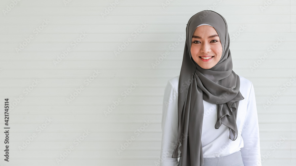 Portrait of cout beautiful Muslim woman wearing hijab traditional religious cloth posing with friendly looking to camera with a lovely smile on white background with copy space. Portrait of cout beautiful Muslim woman wearing hijab traditional religious cloth posing with friendly looking to camera with a lovely smile on white background with copy space.