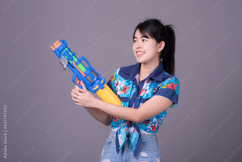 Portrait cheerful young asian woman Wearing a yellow tank top ,holding plastic water gun Smiling and having fun playing in the water Songkran festival, Songkran Thailand. isolated on black background. Portrait cheerful young asian woman Wearing a yellow tank top ,holding plastic water gun Smiling and having fun playing in the water Songkran festival, Songkran Thailand. isolated on black background.