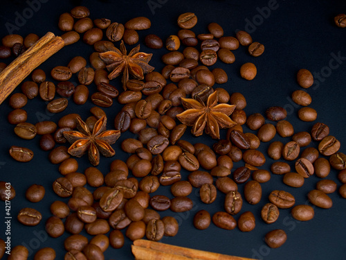 Roasted arabica coffee beans, cinnamon sticks and anise stars on a dark wooden background,close-up