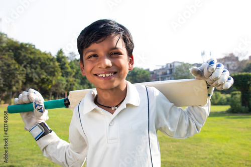 Photography Boy in cricket uniform holding a cricket bat