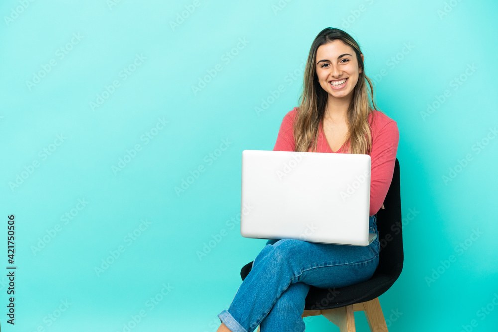 Naklejka premium Young caucasian woman sitting on a chair with her pc isolated on blue background keeping the arms crossed in frontal position