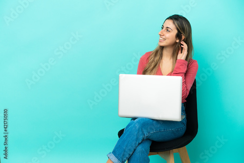 Young caucasian woman sitting on a chair with her pc isolated on blue background thinking an idea © luismolinero