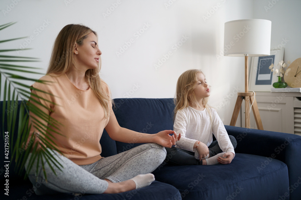 Young mother with little daughter practicing yoga at home. Family fizical activity, sporty mom and kid