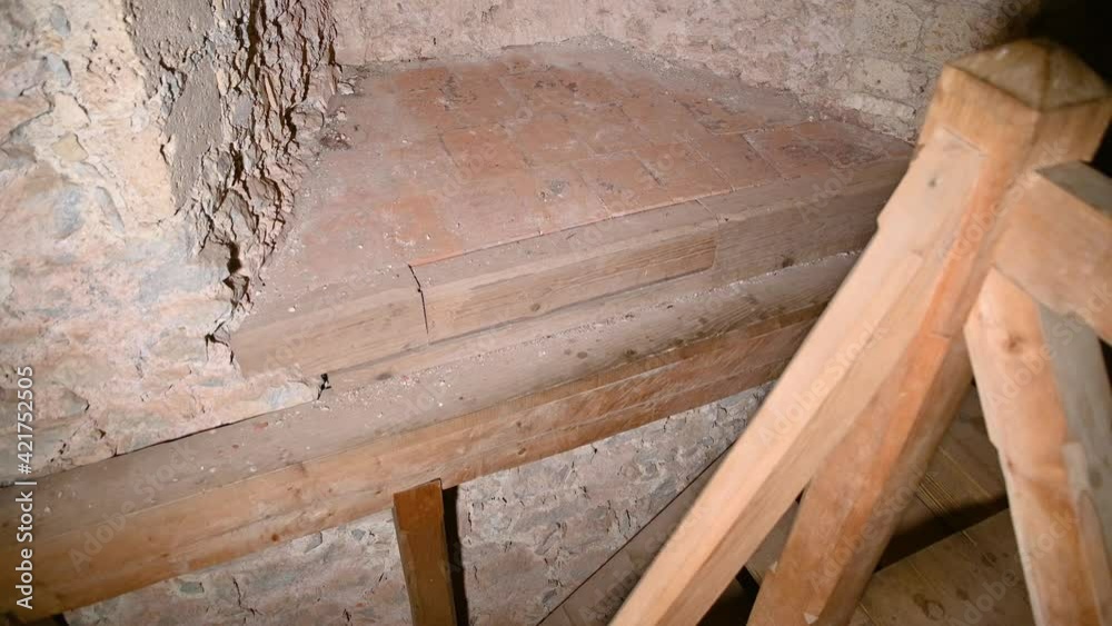 Wooden stairs in old castle tower. Embrasure in thick walls of ancient watchtower. Wooden stairs in middle age structure. Tilt up