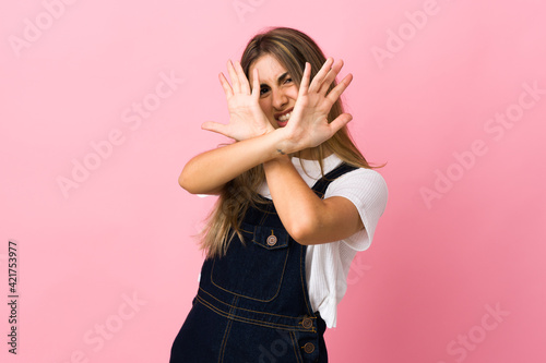 Young woman over isolated pink background nervous stretching hands to the front