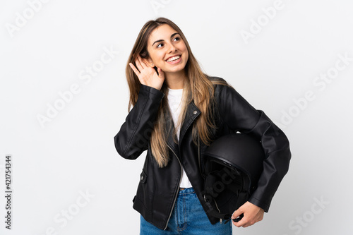Young Woman holding a motorcycle helmet over isolated white background listening something
