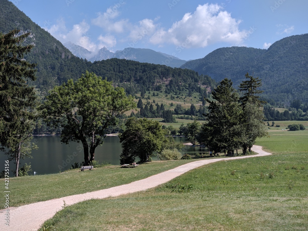 view of an empty path around a lake in the mountains with sand beach in slovenian national park during summer vacation