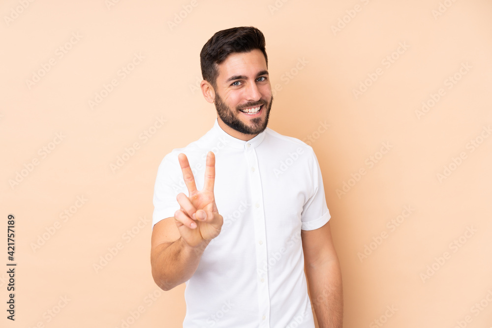 Caucasian handsome man isolated on beige background smiling and showing victory sign Caucasian handsome man isolated on beige background smiling and showing victory sign