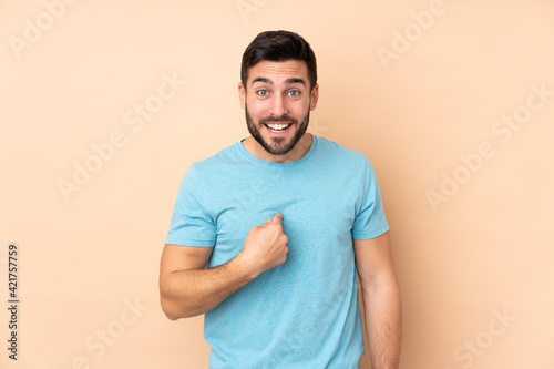 Caucasian handsome man isolated on beige background with surprise facial expression