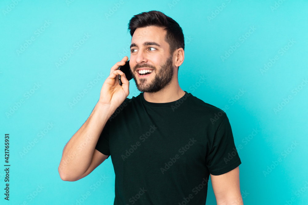 Caucasian handsome man isolated on blue background keeping a conversation with the mobile phone Caucasian handsome man isolated on blue background keeping a conversation with the mobile phone
