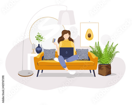 Girl with laptop and credit card. woman sitting on sofa - concept of creative and remote work in home office or online shopping. Home living room interior.