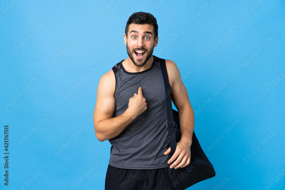Young sport man with sport bag isolated on blue background with surprise facial expression Young sport man with sport bag isolated on blue background with surprise facial expression