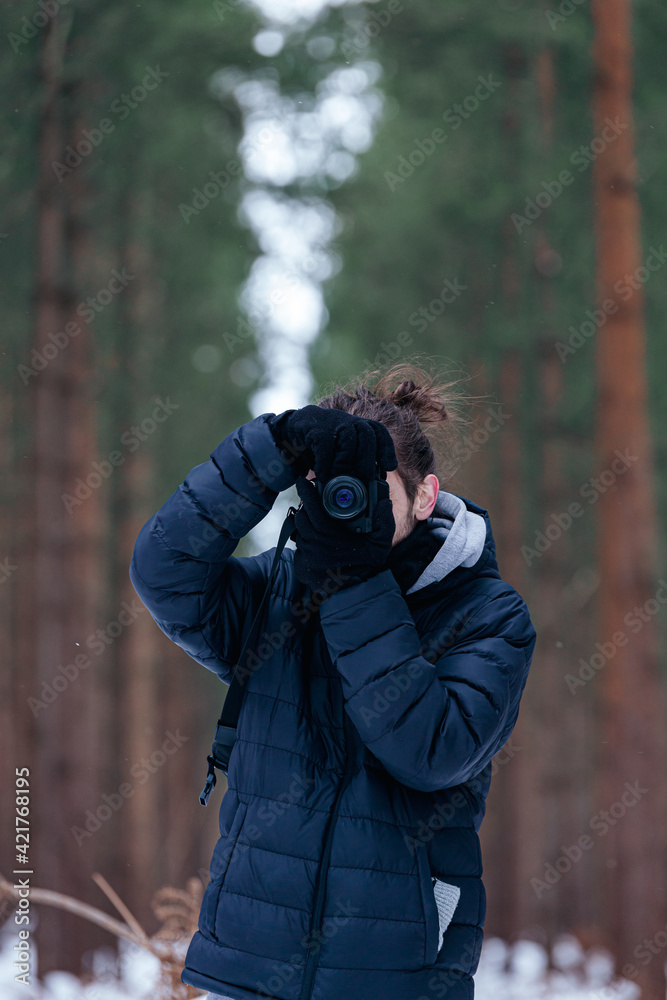 Unknown male standing in a snowy forest holding a camera up to his eye taking a photo looking into camera Unknown male standing in a snowy forest holding a camera up to his eye taking a photo looking into camera