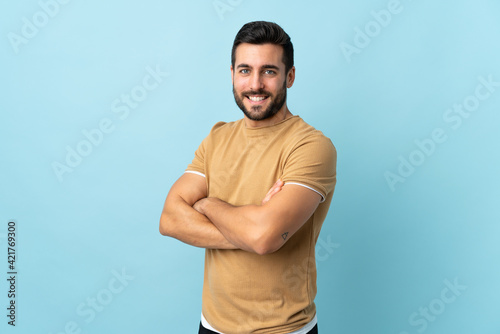 Young handsome man with beard over isolated background with arms crossed and looking forward