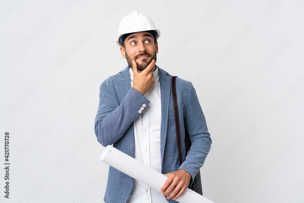 Young architect man with helmet and holding blueprints isolated on white background thinking an idea while looking up Young architect man with helmet and holding blueprints isolated on white background thinking an idea while looking up