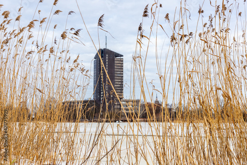 Low angle view from Lucavsala island to TV tower at Zakusala island, Riga, Latvia through the reeds and over the frozen river of Daugava during bright sunny winter day