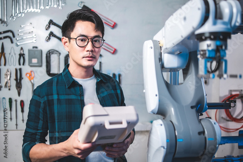 Male Engineers Maintenance Robot Arm at Lab. he are in a High Tech Research Laboratory with Modern Equipment.Professional Japanese Development Engineer is Testing an Artificial Intelligence.