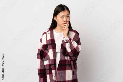 Young Chinese girl over isolated white background and thinking © luismolinero