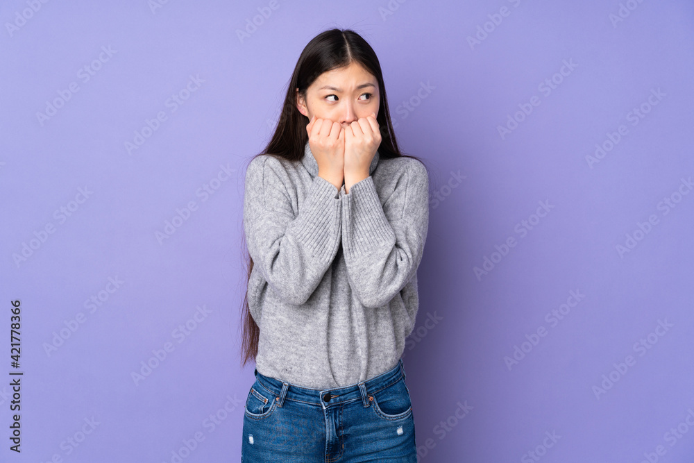 Young asian woman over isolated background nervous and scared putting hands to mouth Young asian woman over isolated background nervous and scared putting hands to mouth