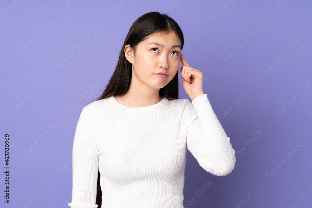 Young asian woman isolated on purple background making the gesture of madness putting finger on the head Young asian woman isolated on purple background making the gesture of madness putting finger on the head