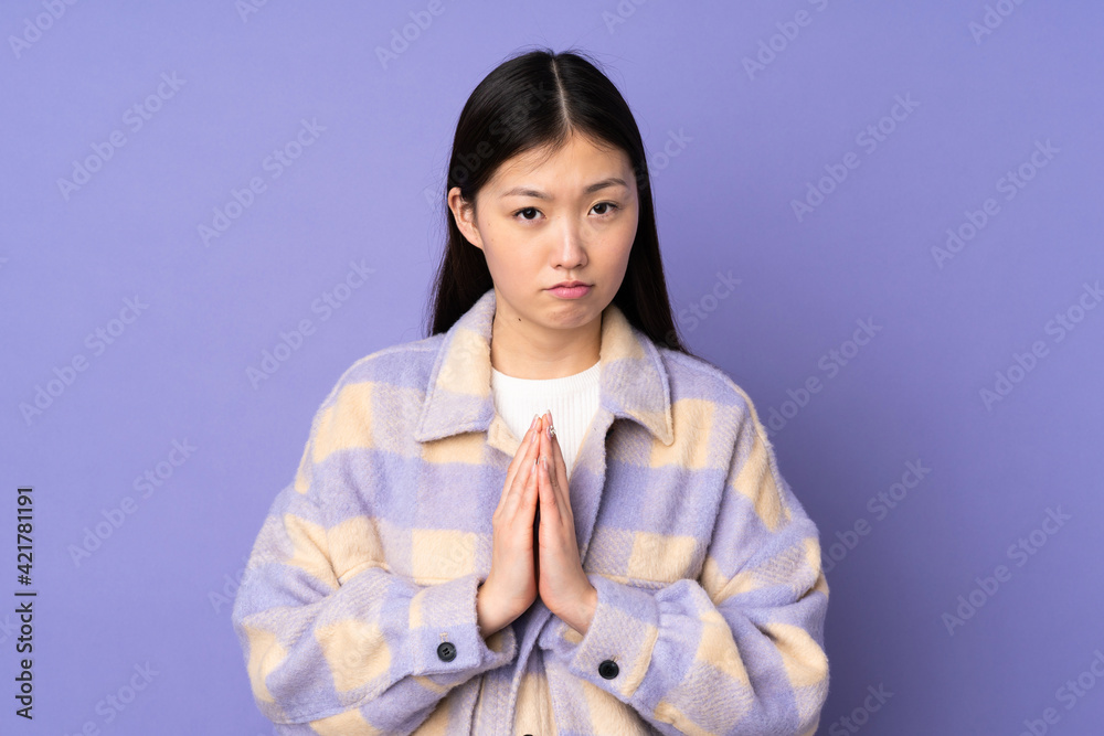 Young asian woman isolated on purple background keeps palm together. Person asks for something Young asian woman isolated on purple background keeps palm together. Person asks for something