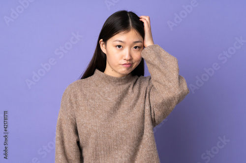 Young asian woman isolated on purple background with an expression of frustration and not understanding © luismolinero
