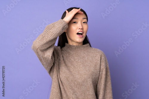 Young asian woman isolated on purple background doing surprise gesture while looking to the side © luismolinero