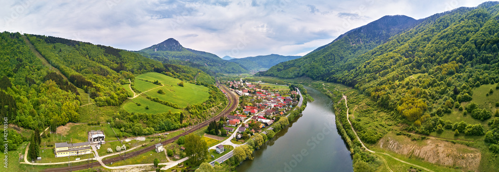 Village, river and road in mountain valley. Green mountain meadows and hills. Kraľoviansky meander on river Bar. Spring panorama