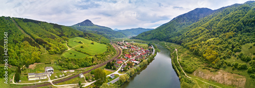 Village, river and road in mountain valley. Green mountain meadows and hills. Kraľoviansky meander on river Bar. Spring panorama photo