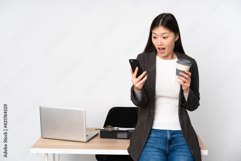 Business asian woman in her workplace isolated on white background holding coffee to take away and a mobile Business asian woman in her workplace isolated on white background holding coffee to take away and a mobile