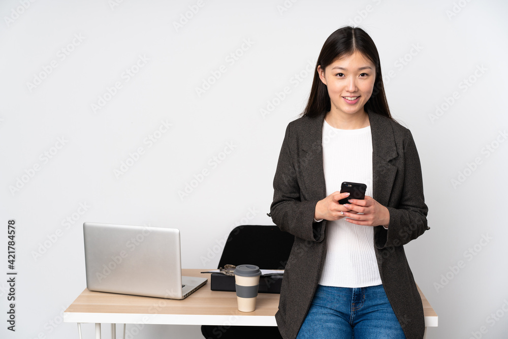 Business asian woman in her workplace isolated on white background sending a message with the mobile Business asian woman in her workplace isolated on white background sending a message with the mobile