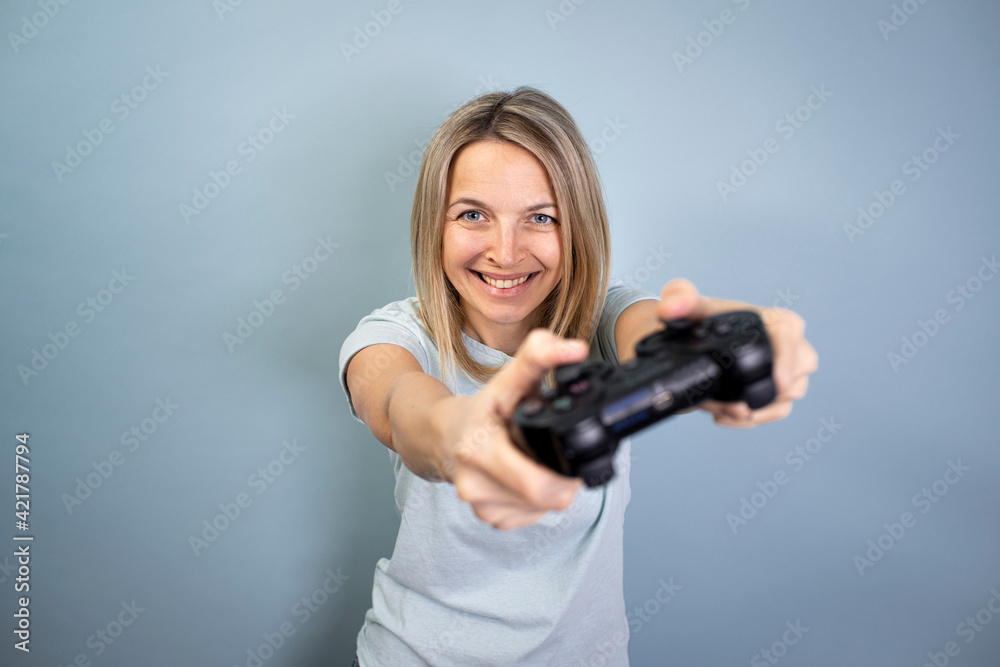 pretty young blond attractive woman posing on blue background with game controller in hand in studio