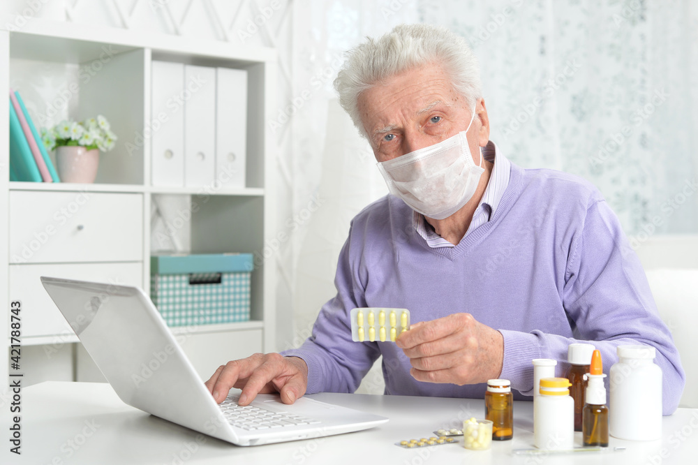 ill senior man with facial mask using laptop ill senior man with facial mask using laptop